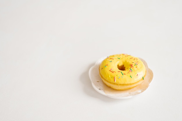 Sirva o donut amarelo polvilhado em um prato branco Conceito de poder criativo e minimalista vista superior de uma superfície plana com espaço de cópia