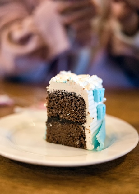 Sirva un trozo de pastel de chocolate con crema batida en un plato blanco para celebrar el cumpleaños