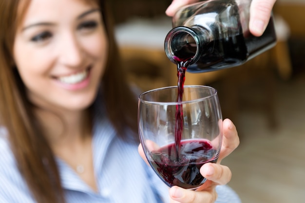 Sirva el vino tinto en el vaso de una chica bonita.