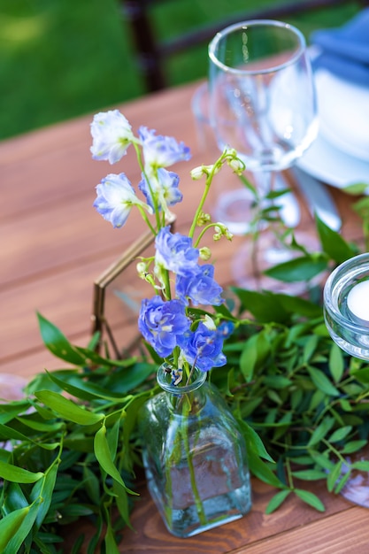 Se sirve una mesa de madera sin mantel y decorada con flores frescas. Detalles de decoraciones festivas con flores frescas.