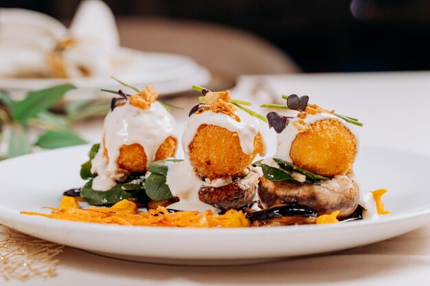 Se sirven bolas de queso frito sobre una almohada de champiñones y berenjenas listas para comer Menú del restaurante