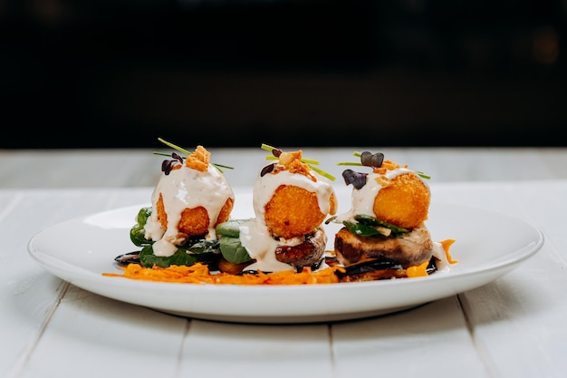 Se sirven bolas de queso frito sobre una almohada de champiñones y berenjenas listas para comer Menú del restaurante