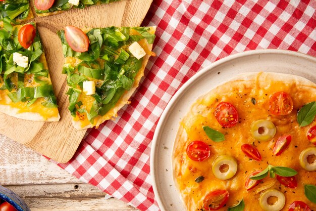 Se sirven pizzas con tomates, rúcula y queso en un plato de cerámica hecho a mano en la vista superior