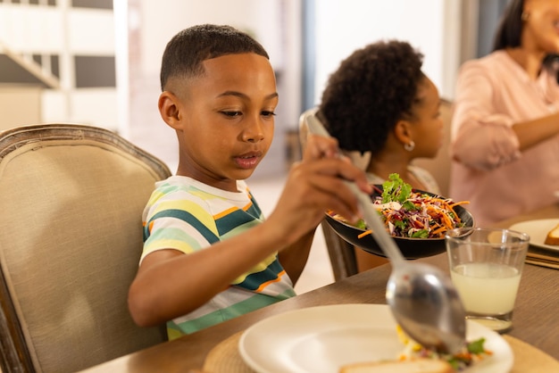 Sirviendo ensalada en la mesa de la cena niño disfrutando de la comida familiar con los parientes