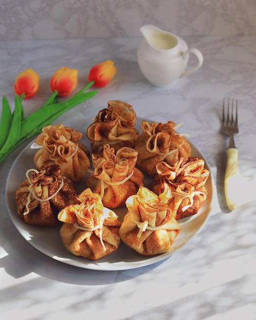 Sirviendo la mesa para Maslenitsa con tortitas en forma de bolsitas de leche y tulipanes