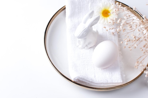 Sirviendo la mesa de Pascua Un plato con un tenedor de servilleta blanco y un huevo de Pascua sobre un fondo blanco