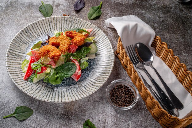 Sirviendo un plato de la carta del restaurante. Langostinos rebozados con limón y ensalada en un plato contra una mesa de piedra gris, un sabroso aperitivo