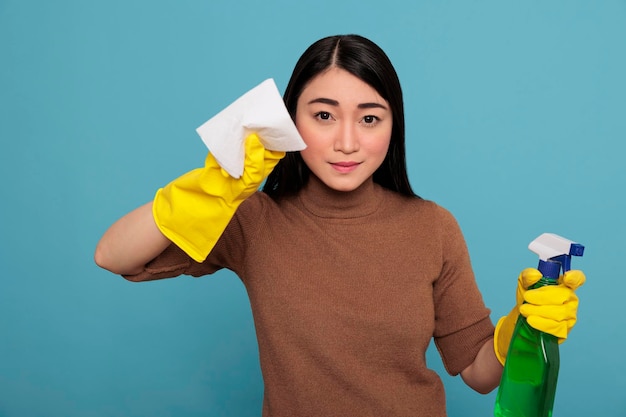 Sirvienta asiática sonriente y feliz del trabajo diario de limpieza con papel tisú y spray detergente, concepto de hogar de limpieza, mujer optimista satisfecha con un estado mental positivo