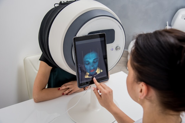 Foto sistema de análisis de piel facial. cosmetóloga analizar cara de mujer. tecnologías modernas