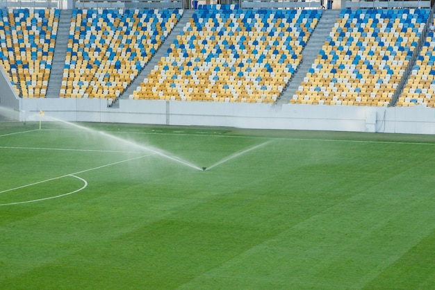 Sistema automático de riego de césped en el estadio Una cancha de fútbol en un pequeño pueblo de provincia Aspersores subterráneos chorros de agua