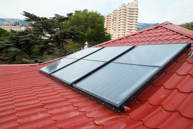 Sistema de calentamiento de agua solar (geliosystem) en el techo de la casa roja.