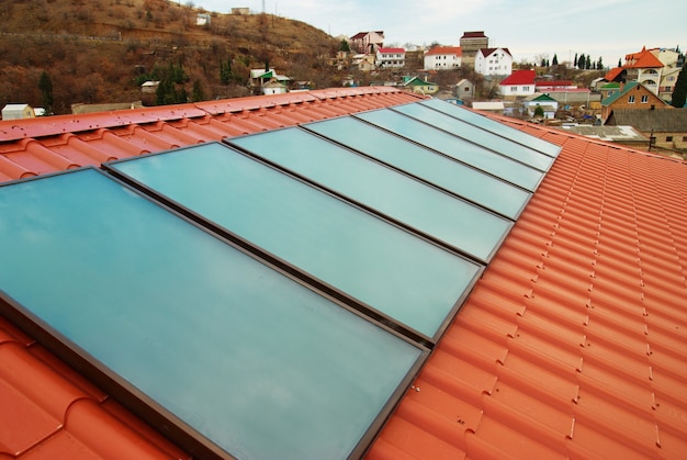 Sistema de calentamiento de agua solar (geliosystem) en el techo de la casa roja.