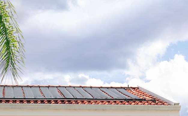 Sistema de aquecimento de água no telhado da casa em um dia ensolarado e nublado