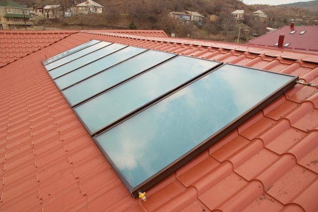 Sistema de aquecimento solar de água geliosystem no telhado vermelho da casa.