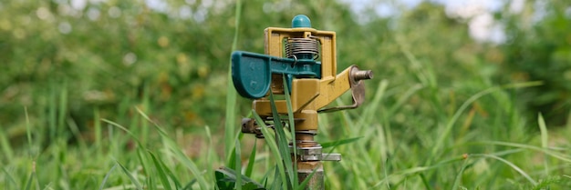 Sistema de irrigação de gramado de metal na grama verde closeup conceito de cuidado de jardim