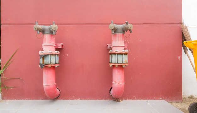 Foto sistema de tubulação de metal do prédio em uma parede de concreto vermelho