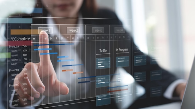Sistema de gestión de proyectos: el gerente de proyecto trabaja en una computadora portátil y actualiza las tareas y los hitos, planifica el progreso con la interfaz de programación del gráfico de Gantt para la empresa en una pantalla virtual.