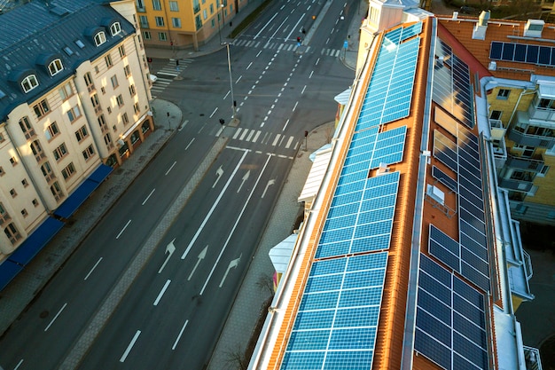 Sistema de paneles fotovoltaicos solares azules en la parte superior del techo del edificio de apartamentos en un día soleado