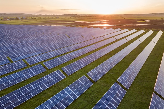 Sistema de paneles fotovoltaicos solares azules que producen energía limpia renovable en el paisaje rural y la puesta del sol