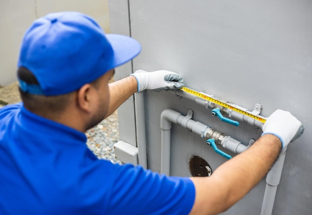 El sistema de tuberías de instalación del trabajador de fontanero masculino utiliza el nivel de cinta métrica para calcular el servicio de comprobación y reparación de fontanería