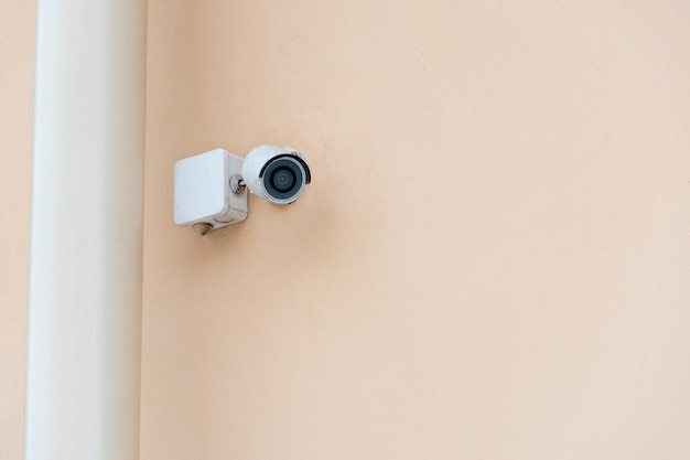 Sistemas de vigilância por vídeo Sistemas de segurança e proteção contra roubo Câmera de segurança CCTV instalada na fachada de um edifício residencial Tecnologia digital fundo laranja