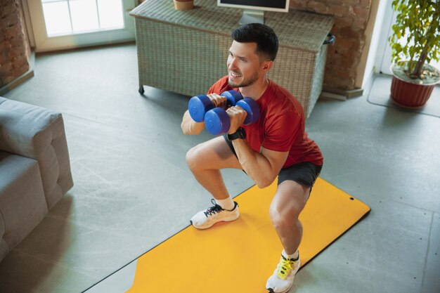 Sit-ups. Junger Kaukasier trainiert zu Hause während der Quarantäne des Coronavirus-Ausbruchs, macht Fitnessübungen, Aerobic. Video aufnehmen oder online streamen. Wellness, Sport, Bewegungskonzept.