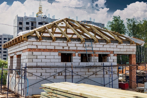 Sitio de construcción de una casa en construcción. Paredes inacabadas de la casa hechas de bloques de hormigón autoclave aireados blancos. Sistema de vigas de madera.