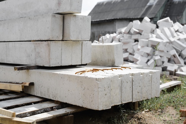 Sitio de construcción cimientos de hormigón bloques grises largos ladrillos losas estrechas de piedra en fila en el sitio de construcción al aire libre