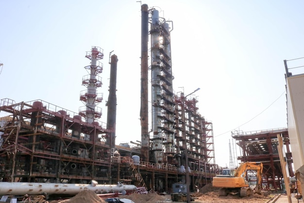 Un sitio de construcción para la construcción de una refinería de petróleo con grandes columnas de rectificación intercambiadores de calor una excavadora en una refinería de petróleo una planta petroquímica