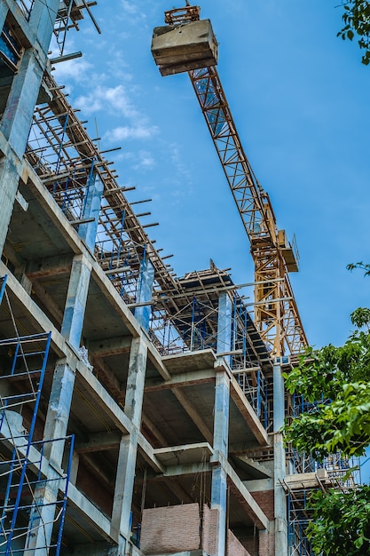 Sitio de la construcción de edificios y grúa contra el cielo azul