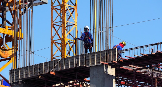 Sitio de construcción de edificios y trabajador de pie sobre acero y material de hormigón y cielo azul.