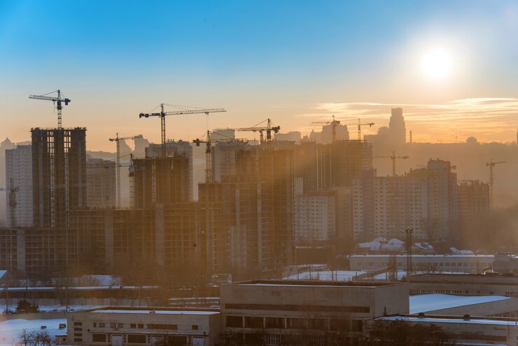 Sitio de construcción con grúas industriales en la ciudad al atardecer