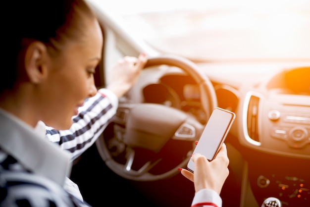 Foto situação perigosa, jovem mulher dirigindo um carro e mensagens de texto no celular.