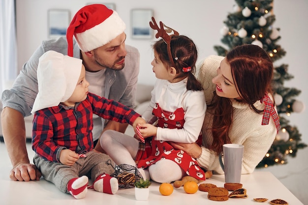 Sitzt gegen Tanne Schöne Familie feiert Neujahr und Weihnachten im Haus zu Hause