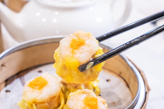 Siu Mai einer von Dim Sum Yum Cha Schweinefleisch und Garnelen gedämpfte Knödel auf dem weißen Hintergrundtisch des Restauranthauses zum Frühstückslebensstil aus nächster Nähe