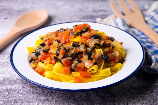 Sizilianische Tagliatelle mit Tomaten und schwarzen Oliven.