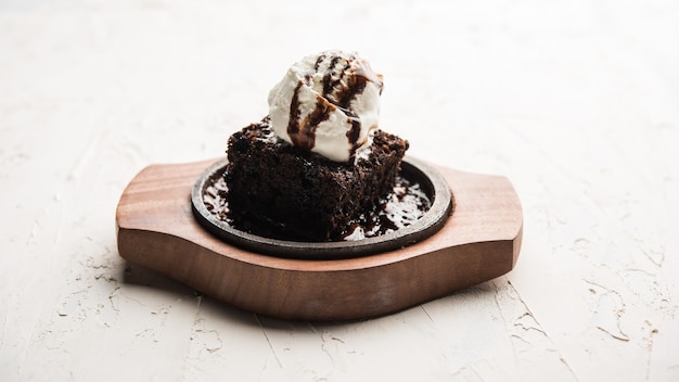 Foto sizzling chocolate brownie ist ein süßes gericht, das aus einer kugel eiscreme besteht und mit einer großzügigen portion geschmolzener schokolade serviert wird. server heiß. selektiver fokus