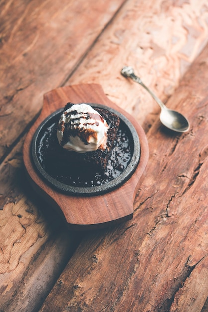 Sizzling Chocolate Brownie ist ein süßes Gericht, das aus einer Kugel Eiscreme besteht und mit einer großzügigen Portion geschmolzener Schokolade serviert wird. Server heiß. selektiver Fokus