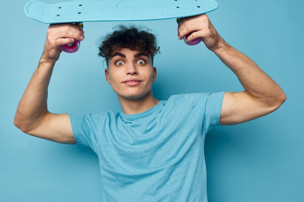 Skate de jovem bonito na mão em camisetas azuis inalteradas