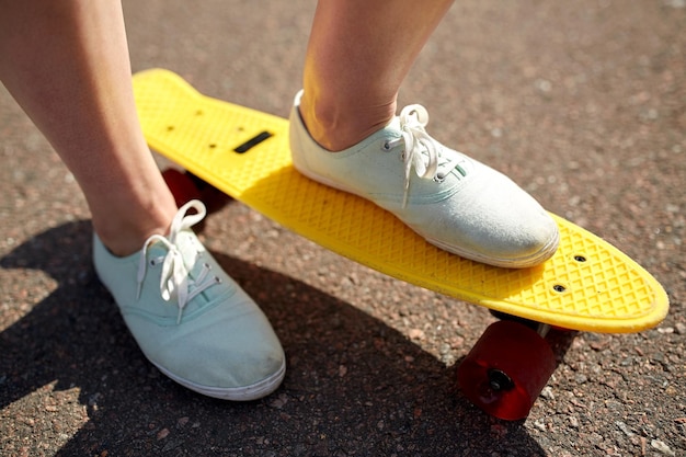 skate, lazer, esporte radical e conceito de pessoas - close-up de pernas de adolescente andando de skate cruzador moderno curto na estrada