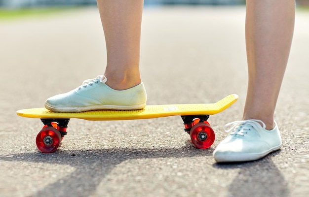 skate, lazer, esporte radical e conceito de pessoas - close-up de pernas de adolescente andando de skate cruzador moderno curto na estrada