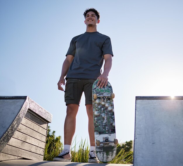 Skateboardsport und Mann auf Rampe im Community Skate Park für Freiheitsübungen und Fitness mit Lächeln und Nachdenken über Zielmotivation und Traum Fröhlicher Skater im Freien für Spaß und Abenteuer