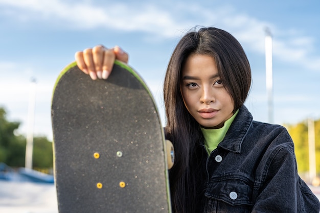 Skater femenino adolescente fresco con estilo en el parque de patinaje