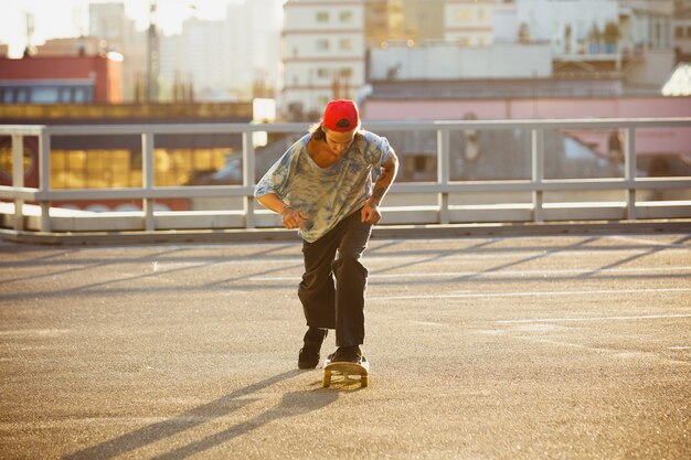 Skater haciendo un truco en las calles de la ciudad en el sol de verano Joven en zapatillas de deporte