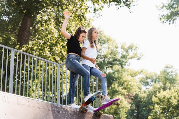 Skater Kinder Mädchen lesen, um bei Sonnenuntergang gemeinsam auf dem Pennyboard auf der Skatesportrampe zu fahren Sportgeräte für Kinder Aktiver Teenager mit Pennyboard auf dem Spielplatz im Skatepark
