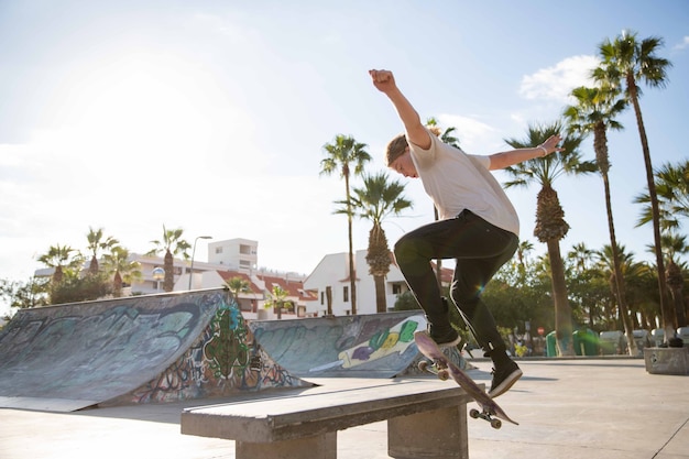 Skater ollies und klettert mit seinem Skateboard im Skatepark auf eine Bank