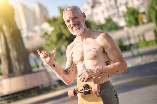 Un skater semidesnudo sosteniendo una patineta