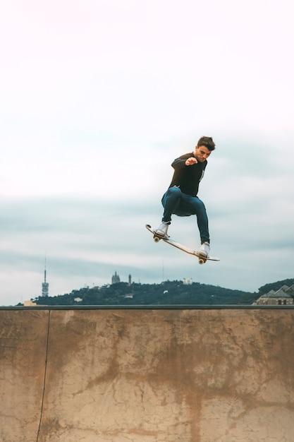 Skater springt mit einem Snakeboard in einem Skatepark hoch in die Luft