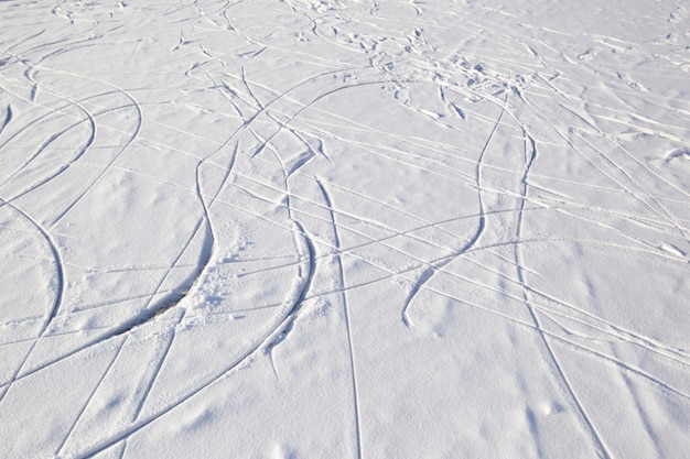 Skatespuren auf Eis mit verschneitem Schnee. Winter-Hintergrund.