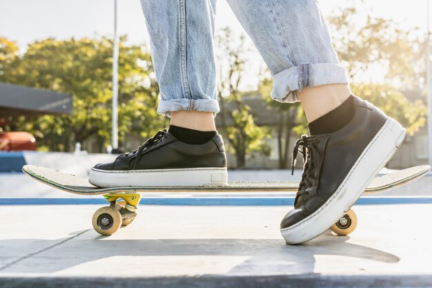 Skatista adolescente elegante e descolada no parque de skate, close-up nos sapatos